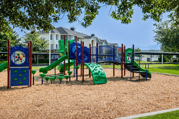 A playground with a green slide and a red and blue sign.